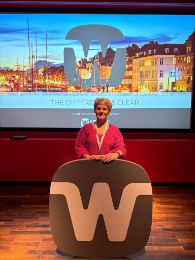 All About Hearing Co-Director and Lead Audiologist, Karen Finch, at the Widex launch event in Copenhagen. Smiling on stage.