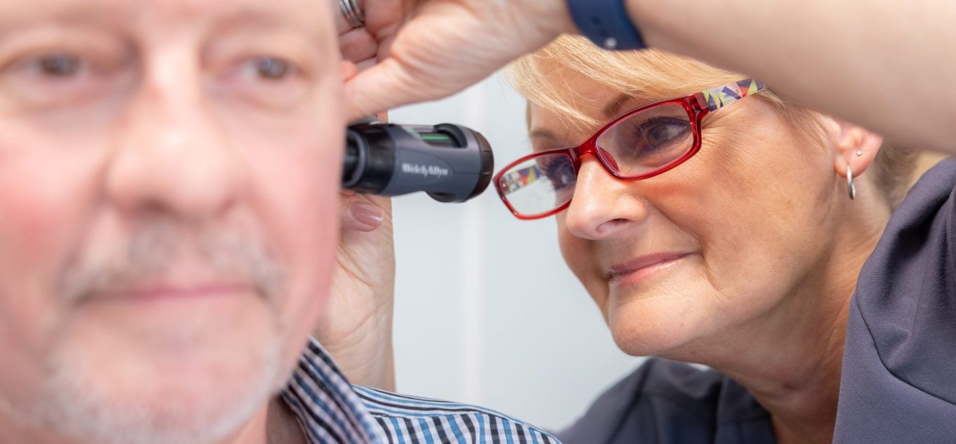 All About Hearing Audiologist, Karen Finch looking at a patient's ear