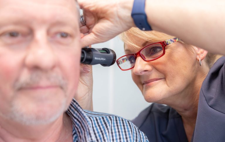 All About Hearing Audiologist, Karen Finch looking into a patient's ear.