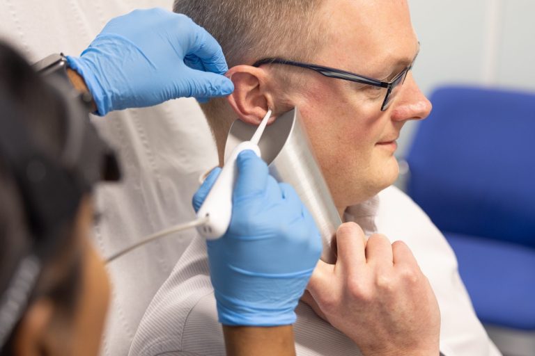 Female Audiologist carrying out ear irrigation on a male patient