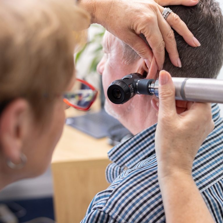 Audiologist Karen Finch using an otoscope to look in a patient's ear