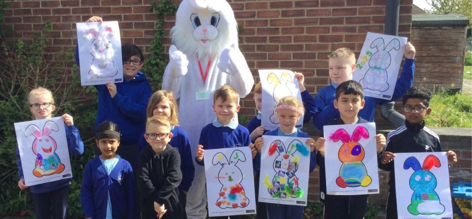 White Easter Bunny standing with children holding up their colourful Easter bunny creations