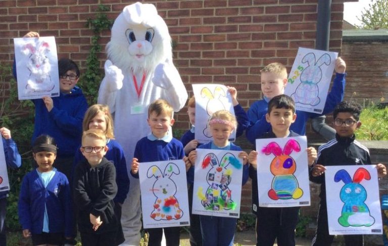White Easter Bunny with children holding up their colourful Easter creations