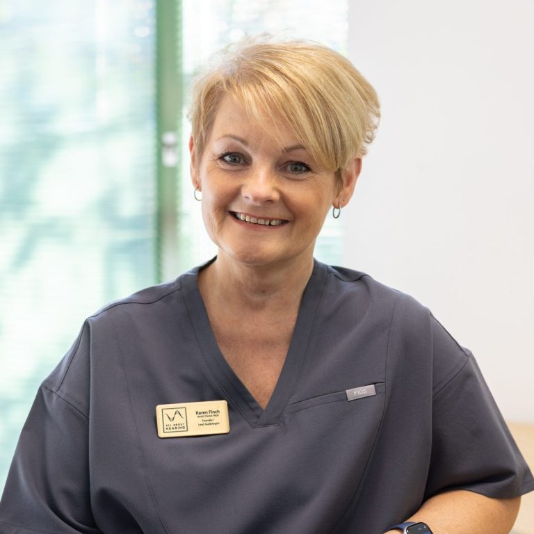 All About Hearing Co-Director Audiologist, Karen Finch, smiling at her desk